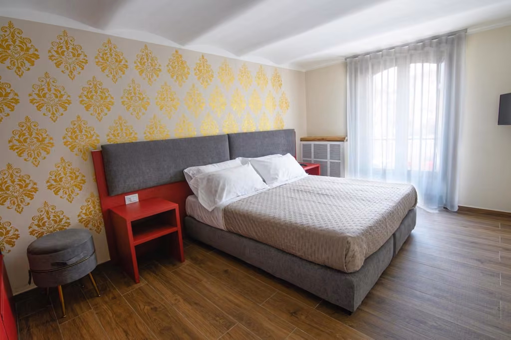 Camera familiare con letto, sedia e finestra del B&B Piazza del Mercato nel centro dell'Aquila